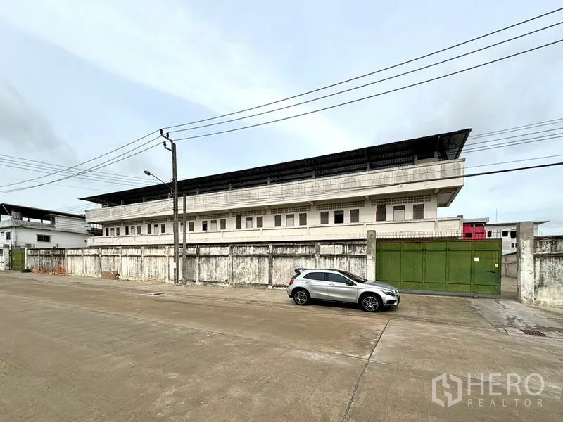 Warehouse for rent in Bang Khun Thian, Bangkok - Street-side façade of the walled warehouse featuring a large sliding green gate.