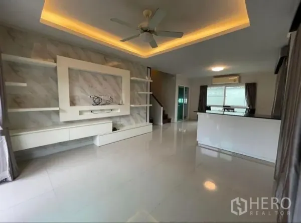 独立式住宅 出售在Bang Phli, Samut Prakan - 明亮的开放式客厅，阶梯天花灯、吊扇与嵌入式电视墙。