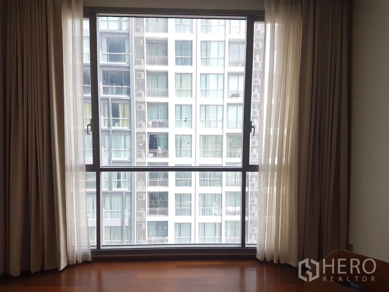 คอนโด ขายในWatthana, Bangkok - หน้าต่างกระจกเต็มบานพร้อมผ้าม่านโปร่ง พื้นไม้ และวิวอาคารคอนโดฝั่งตรงข้าม