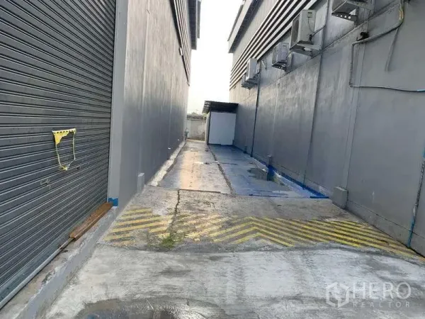 货栈 出租在Bang Phli, Samut Prakan - 仓库建筑间的服务通道，设排水沟、空调外机和装卸坡道标线。