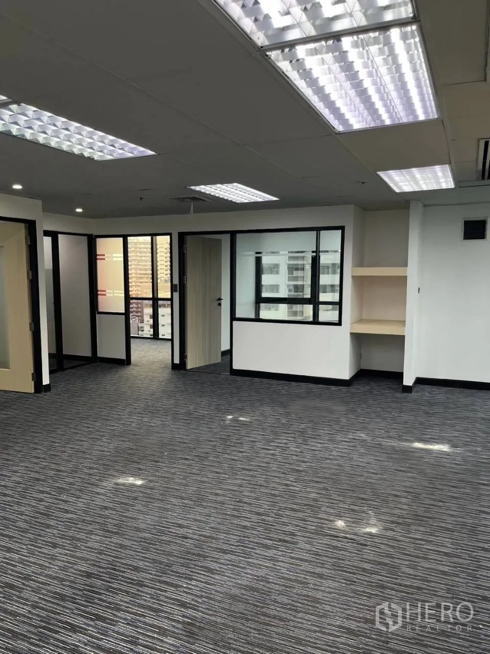 Office Space for rent in Khlong Toei, Bangkok - Bright office area with multiple glass-partitioned rooms and suspended fluorescent lights.