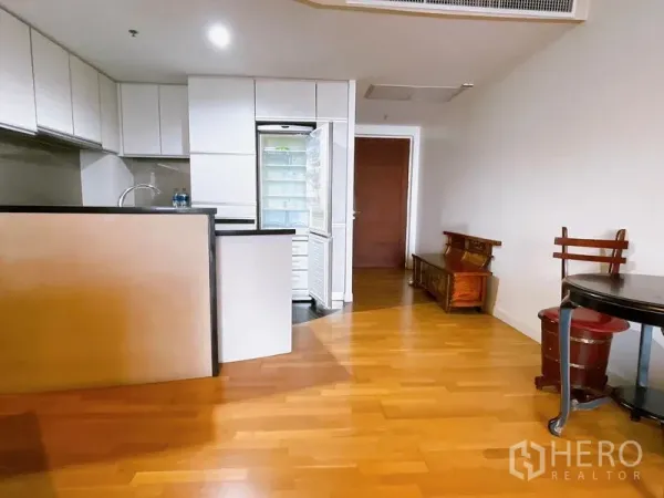 Condominium for rent or sale in Sathon, Bangkok - Open-plan space with breakfast bar, white cabinetry, wood floors and a tall refrigerator.