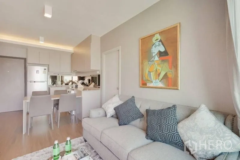 Condominium for rent in Phra Khanong, Bangkok - Cozy living area with tufted sofa, artwork and open kitchen behind.