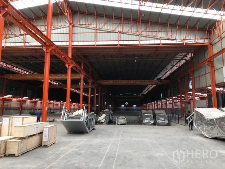 Warehouse for rent in Samut Prakan - Spacious high-bay warehouse in Phra Samut Chedi with orange steel columns and overhead cranes.