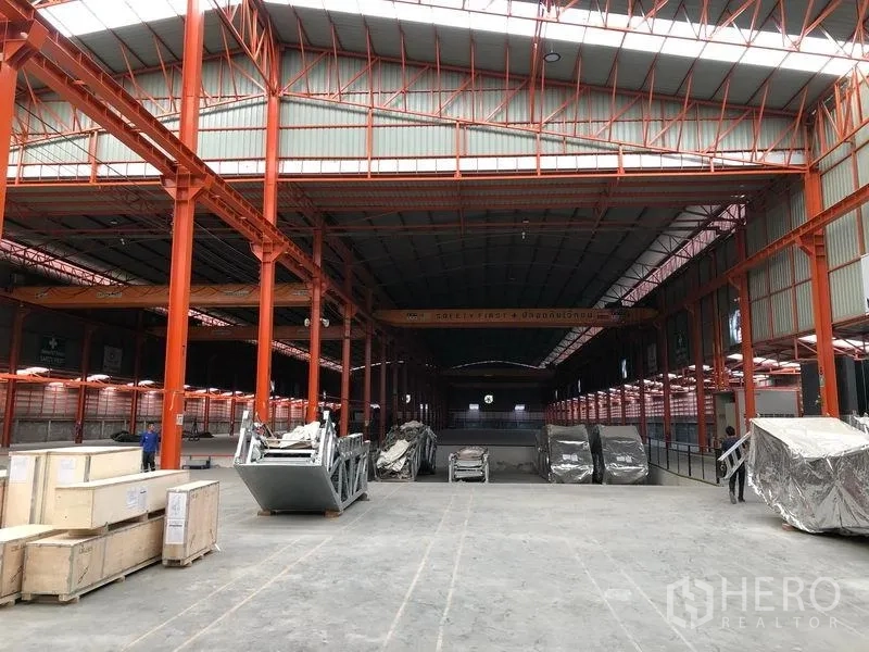 Warehouse for rent in Samut Prakan - Spacious high-bay warehouse in Phra Samut Chedi with orange steel columns and overhead cranes.