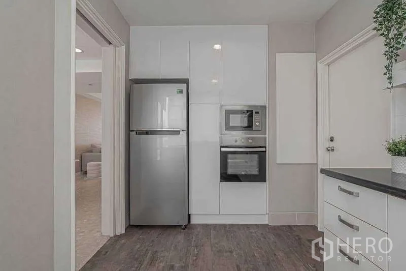 คอนโด ให้เช่าหรือขายในWatthana, Bangkok - ผนังครัวพร้อมเตาอบ ไมโครเวฟ และตู้เย็นสูงในตู้เงา.