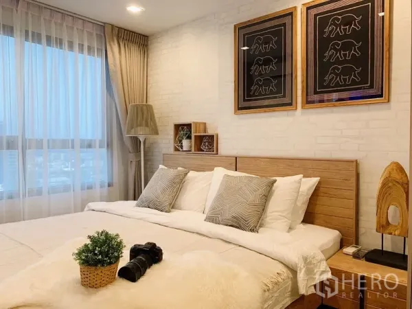 公寓 出租或出售在Phra Khanong, Bangkok - 温馨卧室，大窗与窗帘、木质床头板及城市风格装饰画。