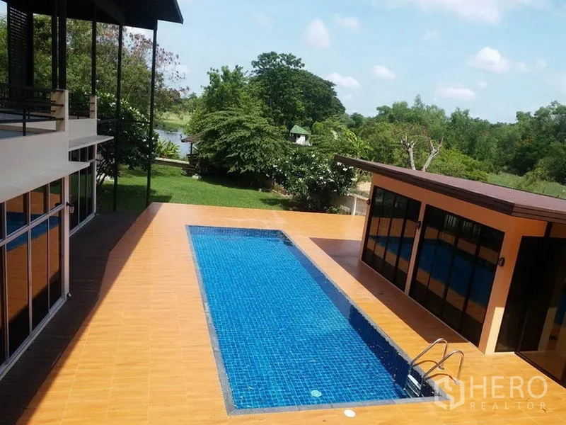 บ้าน ขายในSamut Prakan - สระว่ายน้ำส่วนตัวพร้อมพื้นเดคสีอิฐ มองเห็นสวนสีเขียวและวิวสายน้ำ.