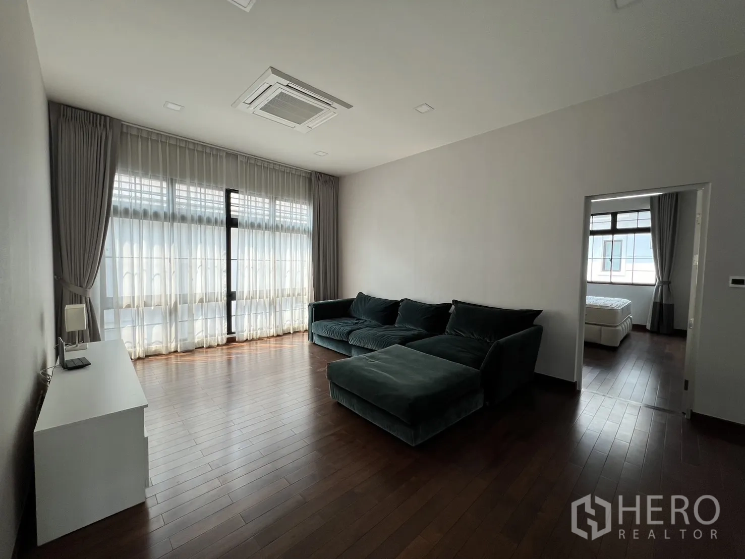 Detached House for rent or sale in Prawet, Bangkok - Upstairs family room with large sectional sofa and sheer curtains.