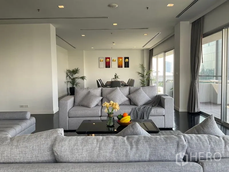 房间 出租在Sathon, Bangkok - 宽敞起居区，灰色沙发面向餐区与露台。