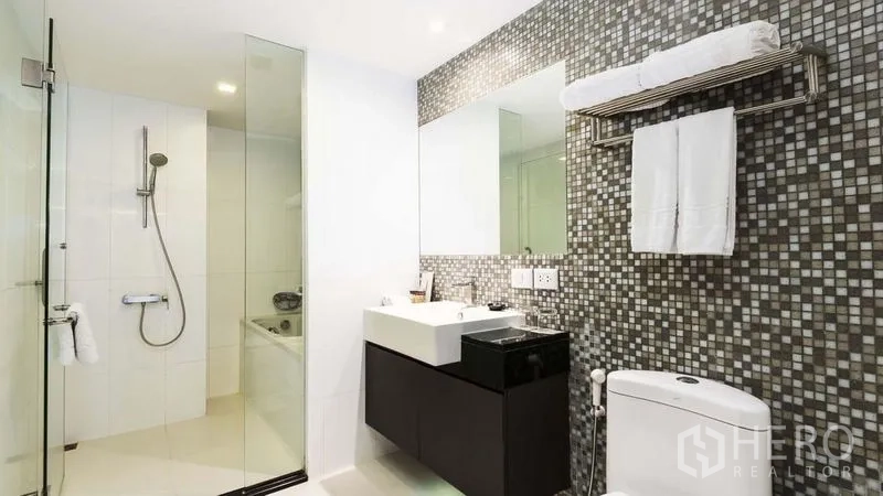 Apartment for rent in Watthana, Bangkok - Modern bathroom with glass shower, mosaic tile feature wall, vanity and toilet.