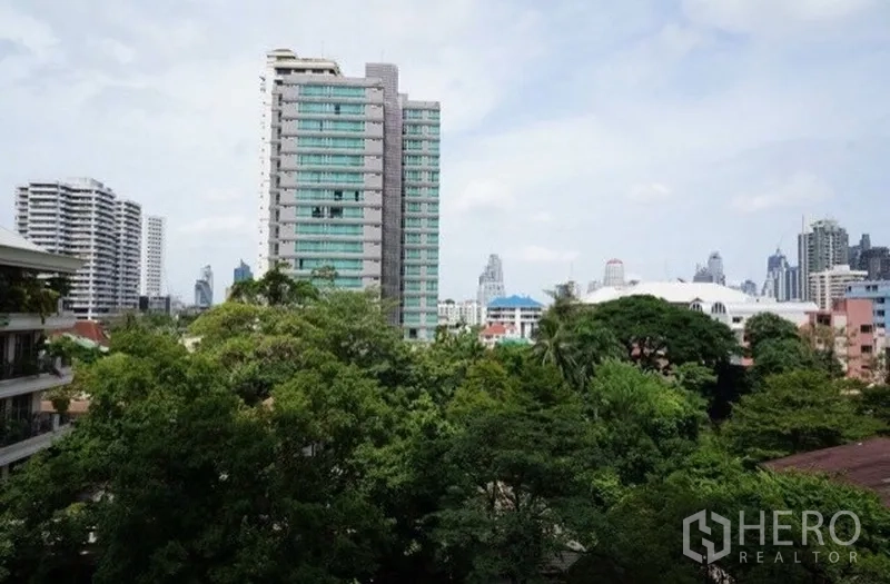 Condominium for rent in Watthana, Bangkok - Balcony view over lush trees toward midrise towers and the Bangkok skyline.