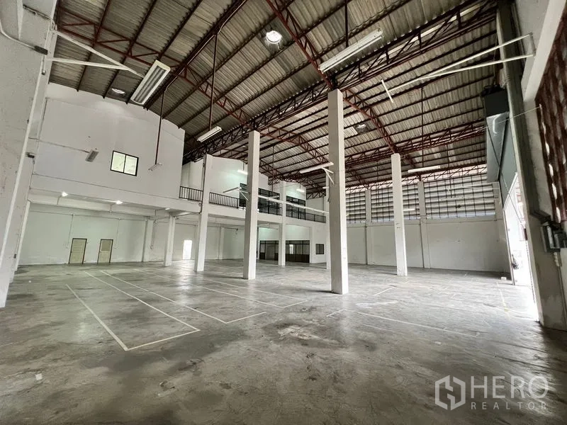 Warehouse for rent in Min Buri, Bangkok - Spacious high‑ceiling warehouse interior with steel columns and mezzanine level.