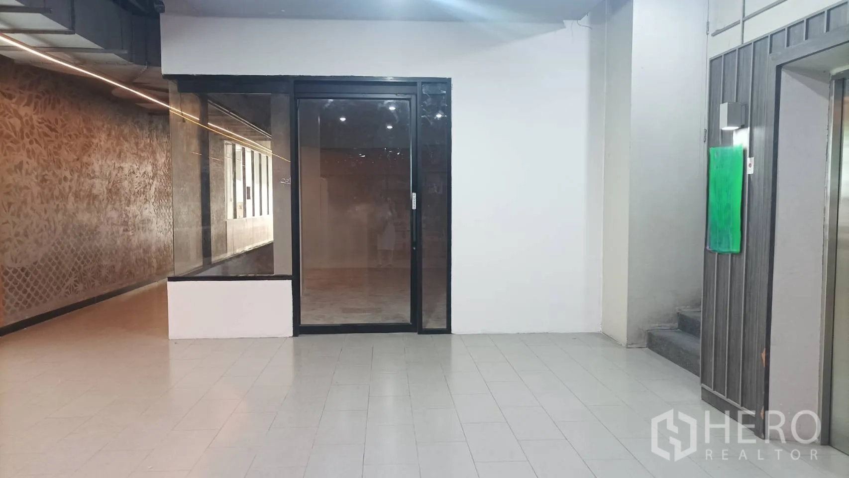 零售空间 出租 - 商铺正面，滑动玻璃门，旁为走廊与电梯厅。