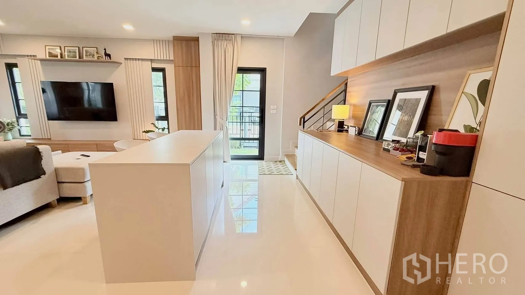 独栋房屋 for rent in Bang Phli, Samut Prakan - 开放式起居区，中央岛台、电视墙、内置柜和楼梯一体布局。