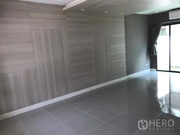 Townhouse for rent - Bright open-plan living room with glossy tile flooring, wood accent wall, air conditioner, and sliding glass doors.