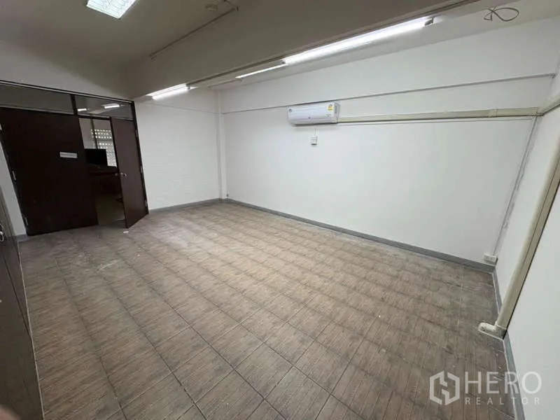 Office Space for rent in Khlong Toei, Bangkok - Empty air-conditioned office room with tiled floor and fluorescent lights.