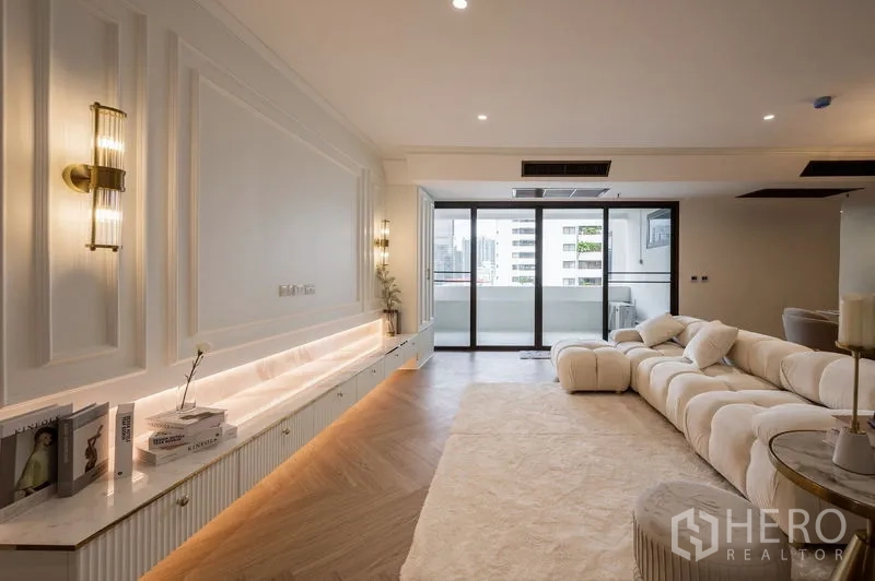 Condominium for sale in Watthana, Bangkok - Elegant living room with wall paneling, built-in console and a city-view balcony.