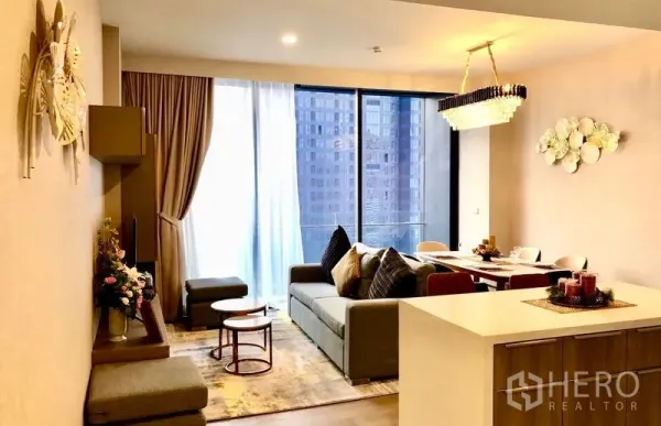 公寓 出租在Watthana, Bangkok - 明亮的客餐厅一体空间，落地窗、沙发与吊灯，可眺望城市景观。