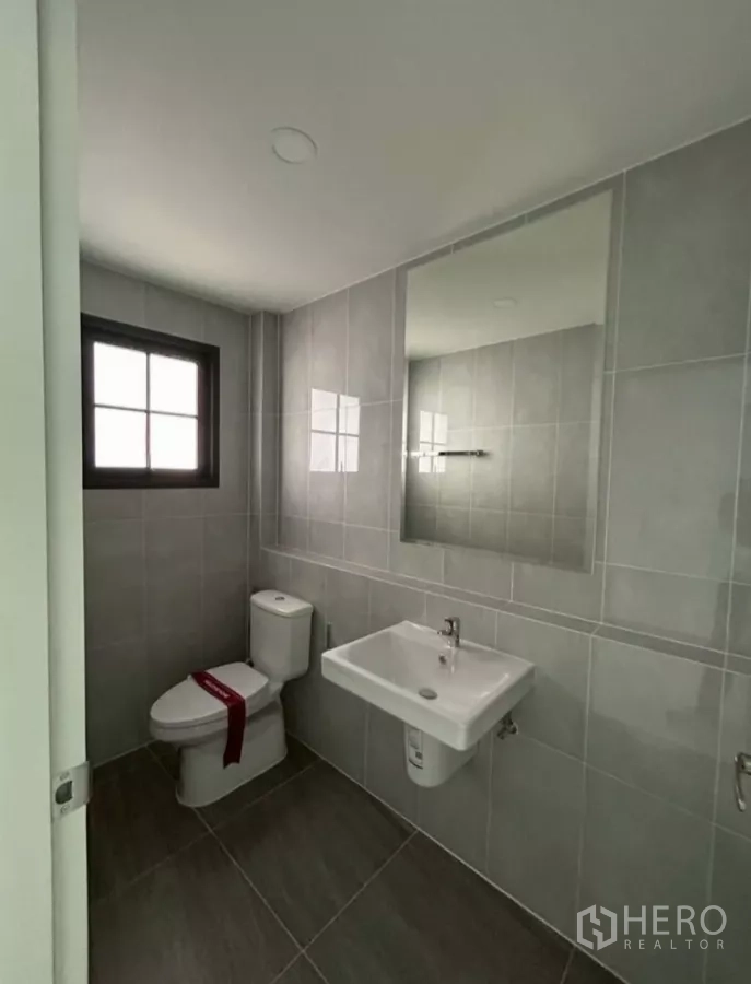 独立式住宅 出租在Bang Phli, Samut Prakan - 紧凑浴室，灰色瓷砖，镜子、坐便器与洗手盆。