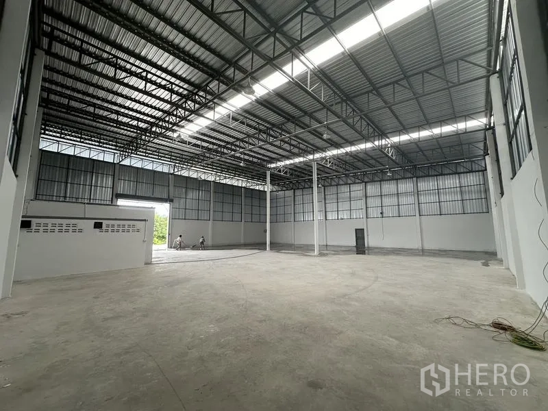 Warehouse for rent in Sai Noi, Nonthaburi - Open storage hall with tall columns, insulated metal roof and smooth concrete floor.