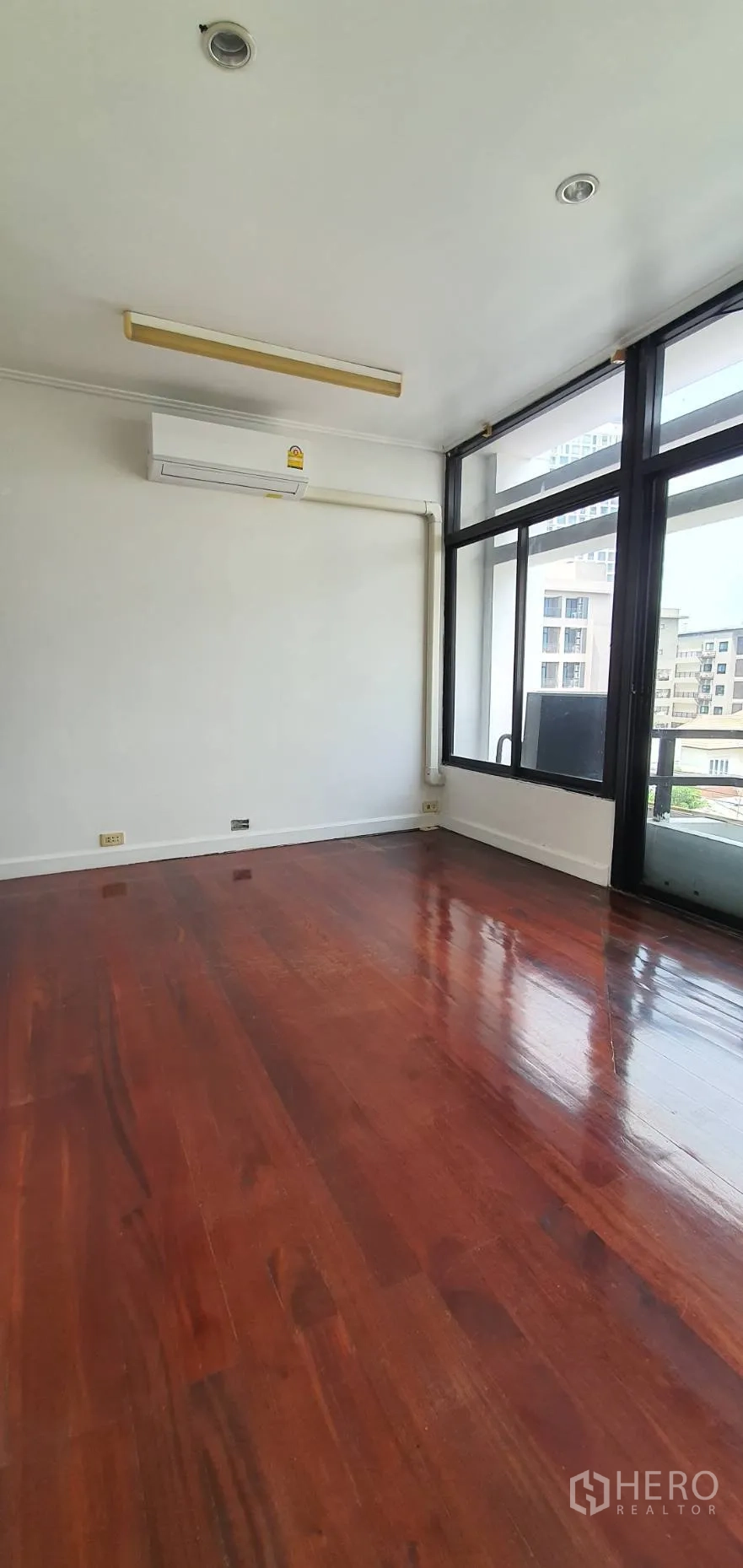 Home Office for rent in Khlong Toei, Bangkok - Sunlit room with polished hardwood floor and sliding glass door to balcony.