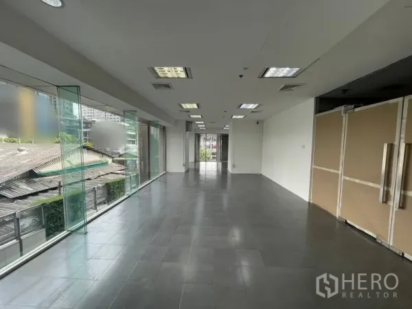 สำนักงาน ให้เช่า - สำนักงานแบบเปิดโล่ง มีกระจกสูงจรดเพดาน พื้นกระเบื้องสีเทา และไฟฝ้าทีบาร์