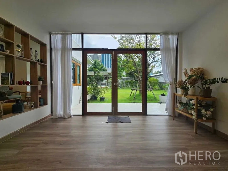 สำนักงานที่บ้าน ให้เช่า - ประตูกระจกเปิดสู่สวน จากห้องที่มีชั้นโชว์และต้นไม้ตกแต่ง