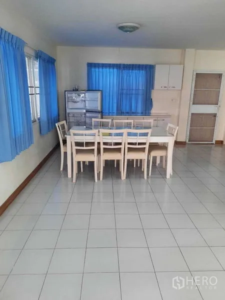 Home Office for rent in Watthana, Bangkok - Dining area with long table and chairs beside blue-curtained windows.