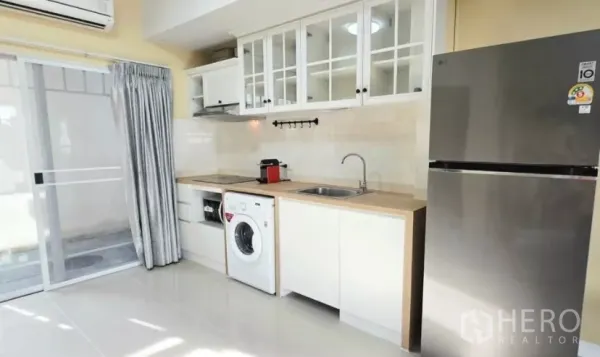 Townhouse for rent in Bang Bo, Samut Prakan - Modern white kitchen with cabinets, hob, hood, washing machine and fridge.