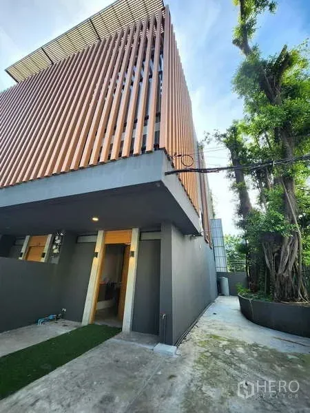 联排别墅 出租在Watthana, Bangkok - 现代联排别墅外立面，竖向木格栅与灰色外墙，私家车道。