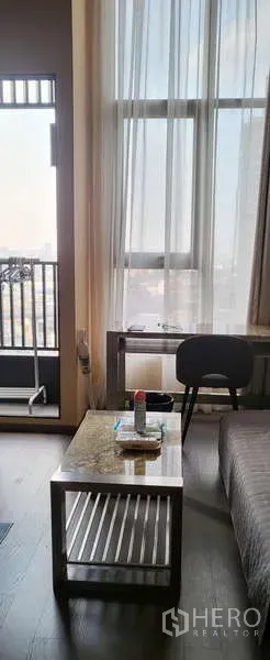 公寓 出租 - 客厅一角，茶几、工作位与阳台门。