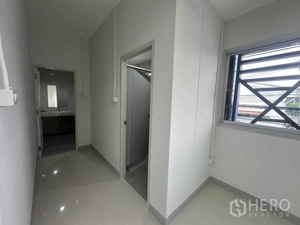 Factory for rent in Bang Phli, Samut Prakan - Hallway beside the office leading to the restroom area with window.