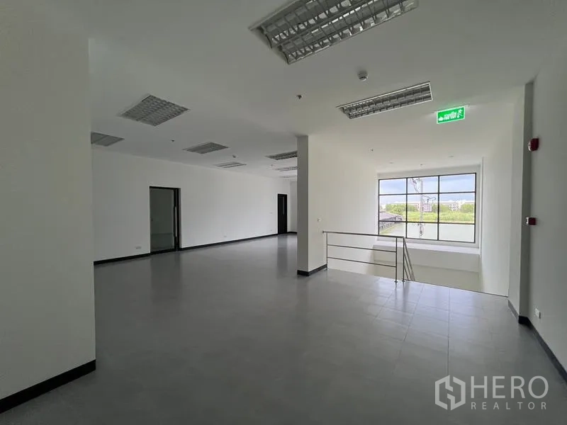 Warehouse for rent in Chon Buri - Second-floor office area with large window and suspended lighting.