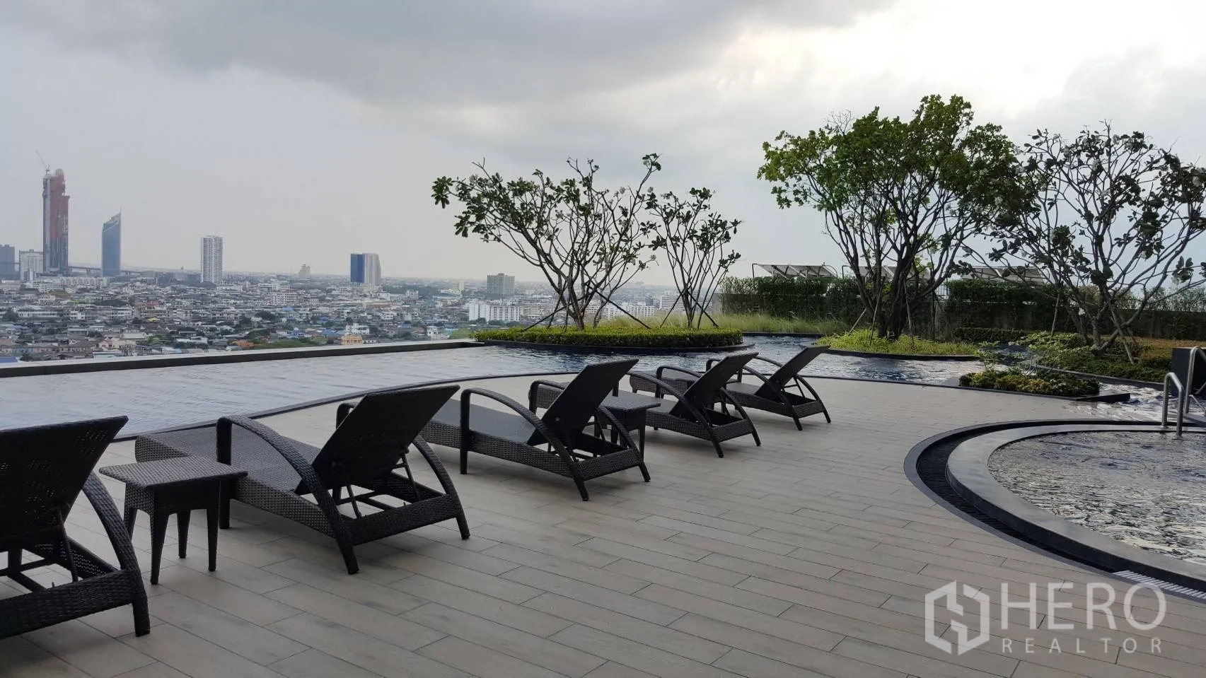 Condominium for rent in Bang Kho Laem, Bangkok - Sky terrace with sun loungers beside a reflective pool and panoramic city views at a riverside condominium in Bangkok.