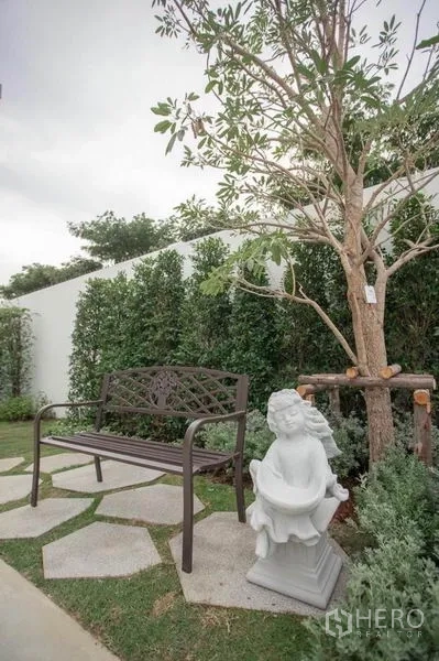 Townhouse for rent in Bang Phli, Samut Prakan - Garden corner with metal bench, stepping stones and decorative statue.