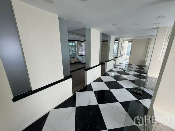 พื้นที่ขายปลีก ให้เช่า - โถงยาวมีเสาและพื้นตารางขาวดำ เชื่อมสู่โซนโชว์สินค้า