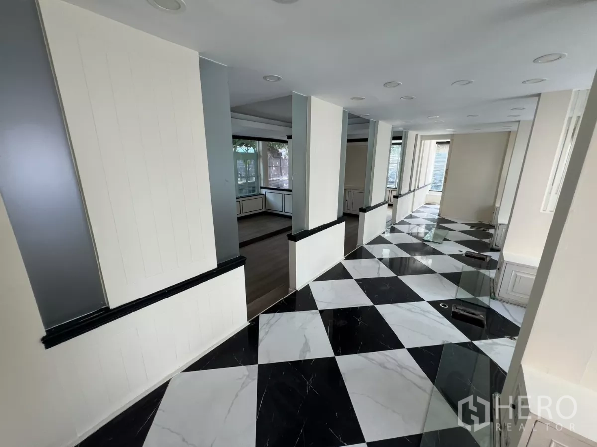 พื้นที่ขายปลีก ให้เช่า - โถงยาวมีเสาและพื้นตารางขาวดำ เชื่อมสู่โซนโชว์สินค้า