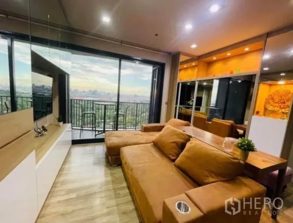 公寓 出租 - 客厅连接落地推拉门与阳台，棕色沙发与镜面柜，远眺城市与公园景观