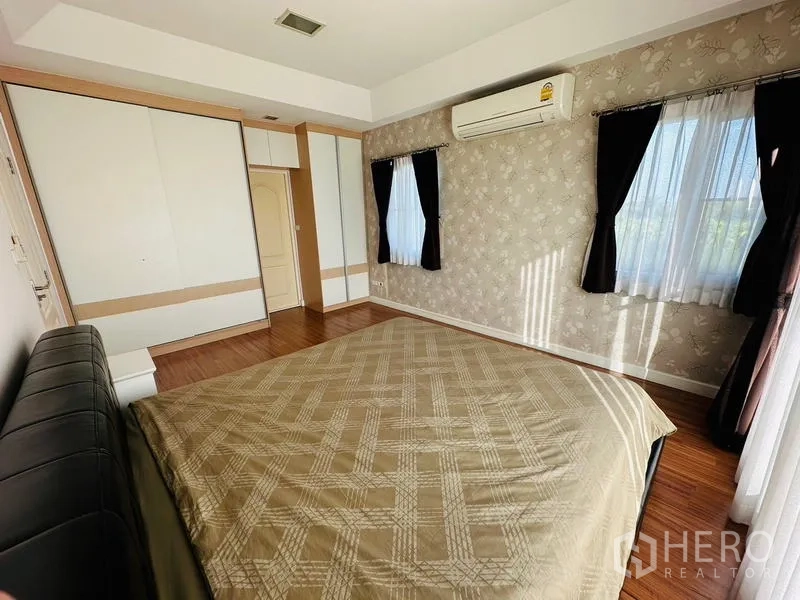Detached House for sale in Prawet, Bangkok - Bedroom with built-in wardrobe, patterned wallpaper and air conditioner.