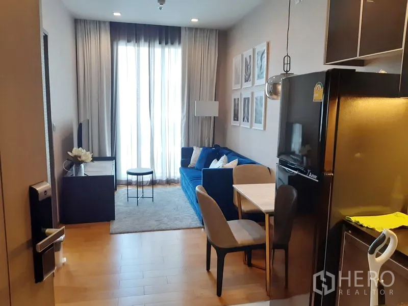 公寓 出租在Khlong Toei, Bangkok - 采光良好的客厅，蓝色沙发、电视柜与落地窗帘。