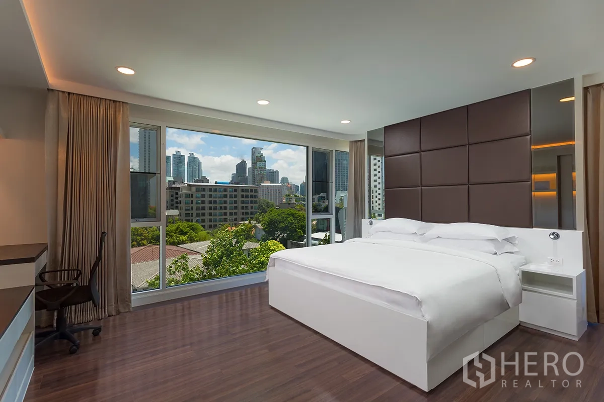 คอนโด for rent in Khlong Toei, Bangkok - ห้องนอนกว้างเตียงใหญ่ กระจกเต็มผนัง มองเห็นวิวเมืองและต้นไม้.