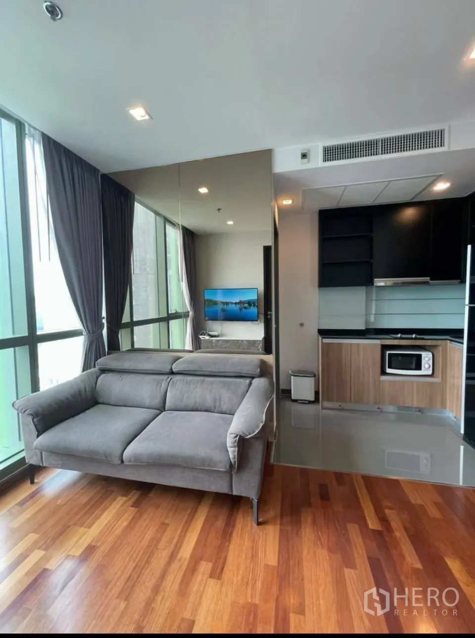 คอนโด for rent in Ratchathewi, Bangkok - ห้องนั่งเล่นมีโซฟาสีเทา หน้าต่างสูง และมองเห็นครัวบิลท์อิน