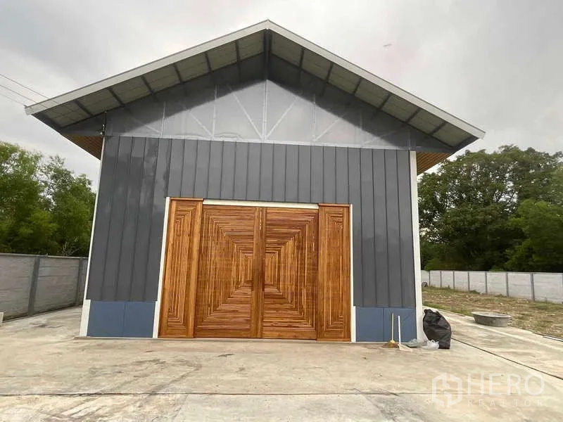 คลังสินค้า ให้เช่าหรือขายในNong Chok, Bangkok - ด้านหน้าตัวโกดังหลังคาจั่ว ผนังเมทัลชีทสีเทา และประตูไม้คู่ขนาดใหญ่