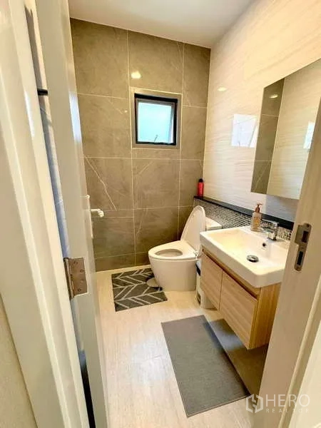 บ้าน ขายในLat Krabang, Bangkok - ห้องน้ำขนาดกะทัดรัด ผนังไทล์สีเข้มพร้อมอ่างล้างหน้าและโถสุขภัณฑ์