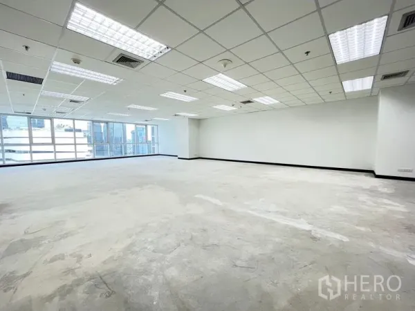 Office Space for rent in Khlong Toei, Bangkok - Open office floor with full-width windows for city views, white walls and suspended grid ceiling.
