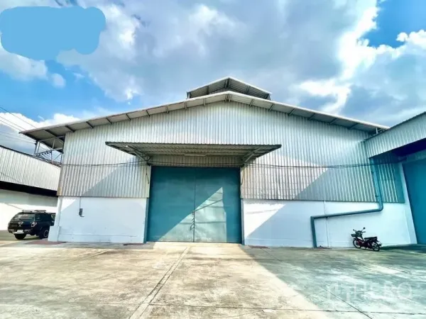 货栈 出租在Pak Kret, Nonthaburi - 帕革区金属外墙仓库外观，宽阔混凝土场地与大型蓝色推拉门