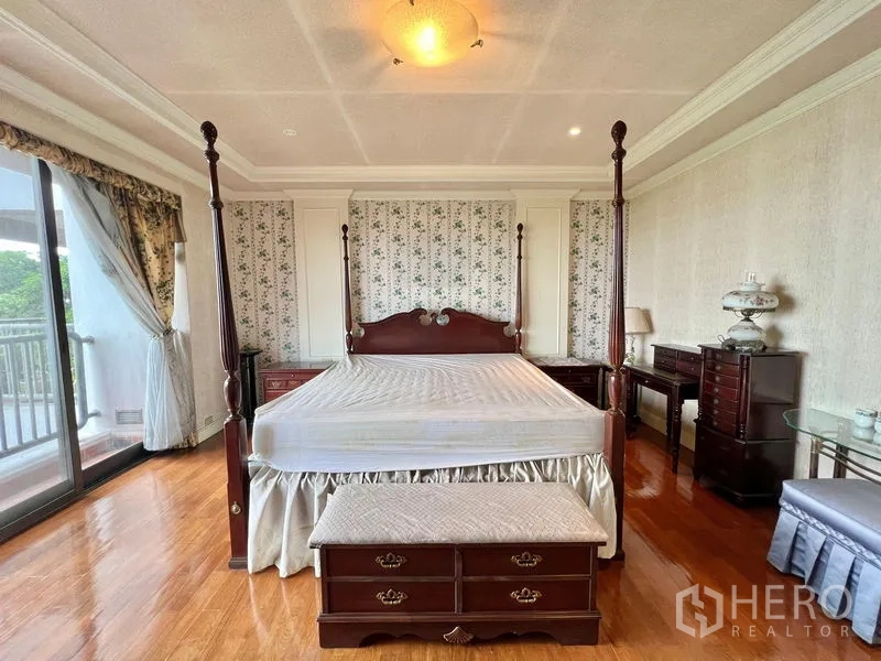 คอนโด ขายในPak Kret, Nonthaburi - ภาพใกล้ห้องนอนใหญ่ เตียงสี่เสา โต๊ะข้างเตียง และประตูกระจกออกระเบียง