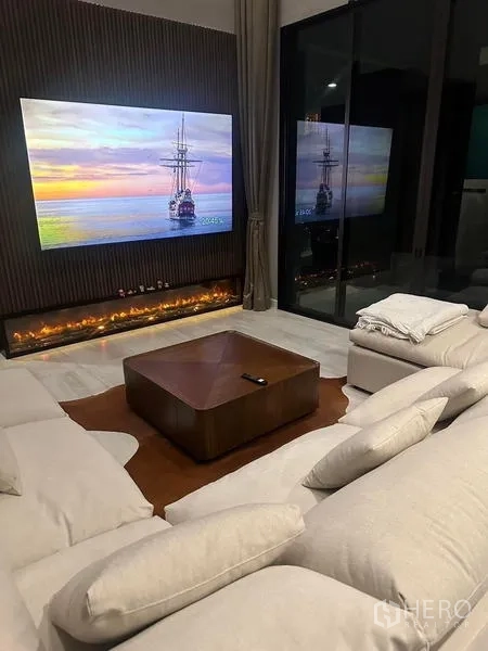 บ้าน ให้เช่าในSaphan Sung, Bangkok - มุมนั่งเล่น ทีวีจอใหญ่ เตาผิงเส้นยาว และโซฟาขนาดใหญ่ยามค่ำ