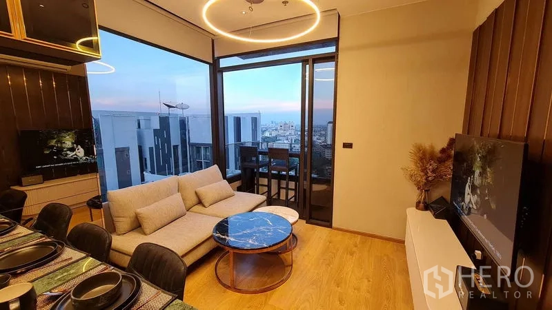 Condominium for rent in Watthana, Bangkok - Open-plan living and dining with floor-to-ceiling windows and balcony access.